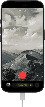 iPhone 18 Pro, parte delantera, muestra un paisaje montañoso, ventana superpuesta del modo Cámara en time-lapse, cable de corriente conectado al puerto de carga
